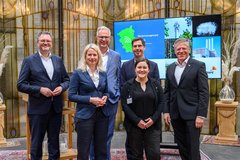 Eine Gruppe von Menschen steht vor einem großen Bildschirm